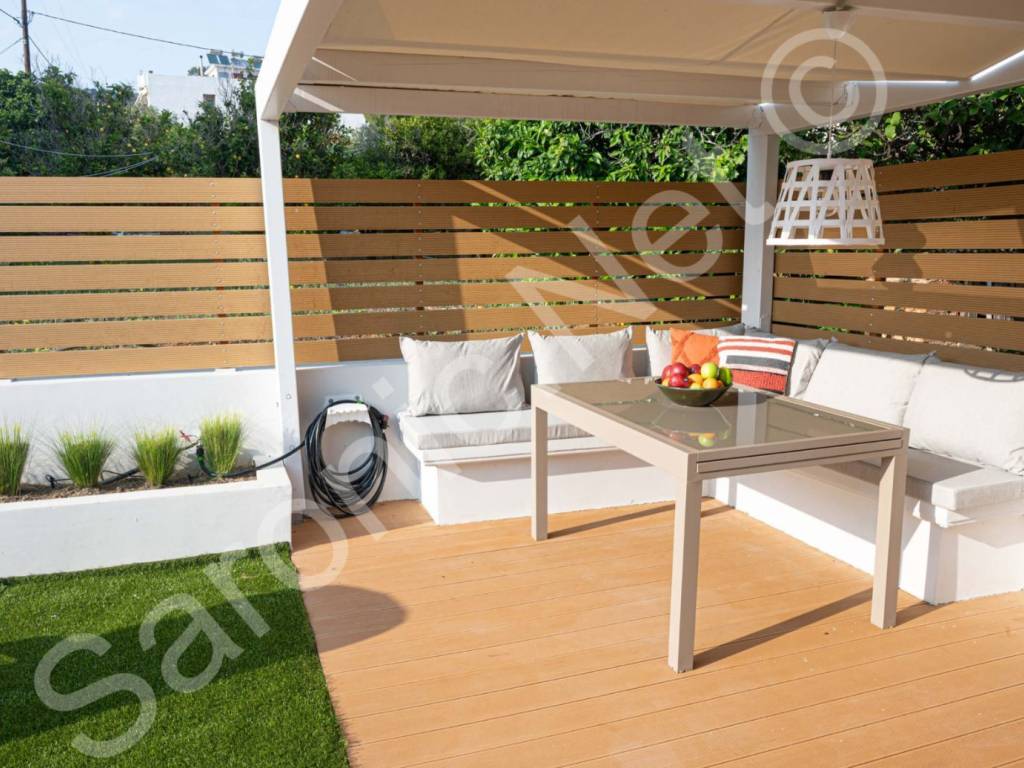 Shaded seating terrace with astroturf and shrub planters.