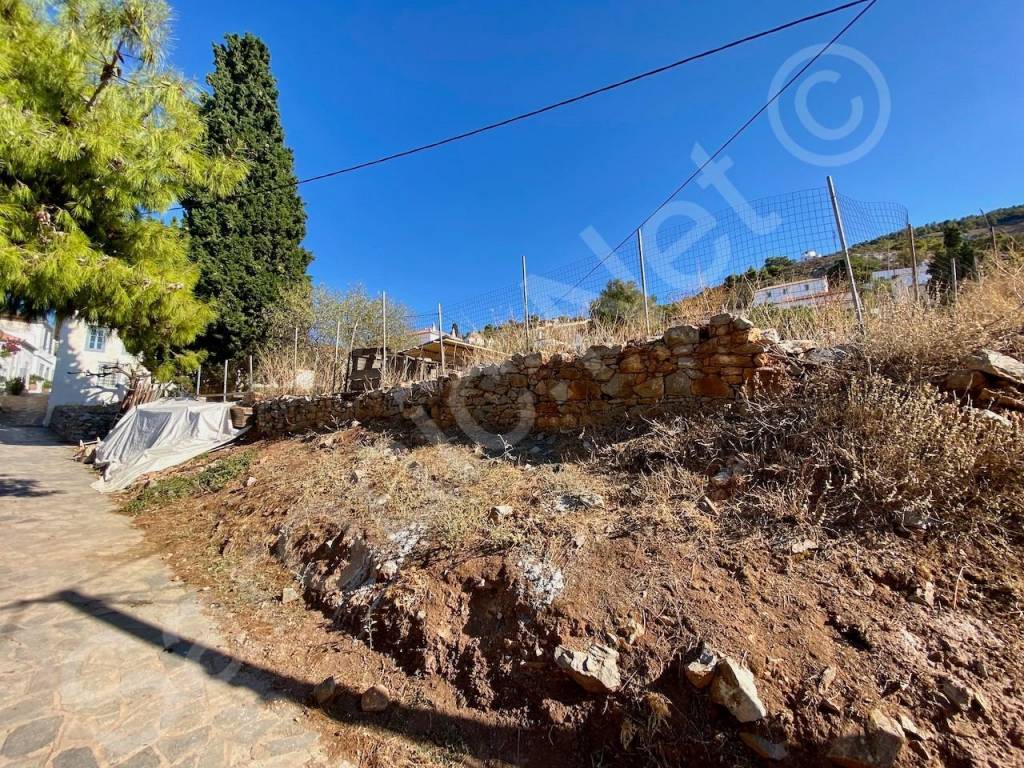 Stone and mesh wire fencing at the bottom of plot of land.