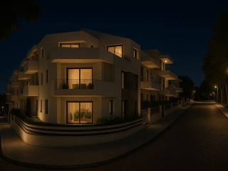 Νεόδμητο κτίριο κατοικιών φωτισμένο τη νύχτα, σε ήσυχο δρόμο