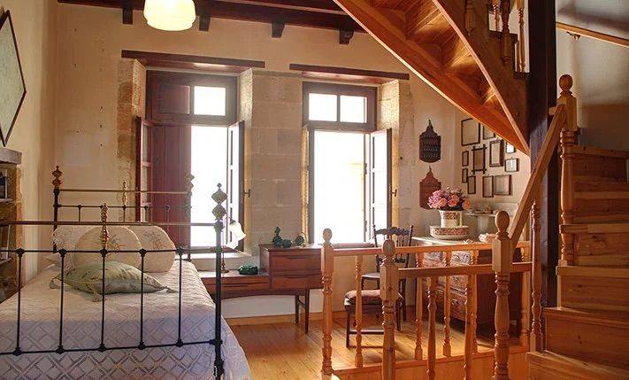 υπνοδωμάτιο με πέτρινους τοίχους και ξύλινη οροφή